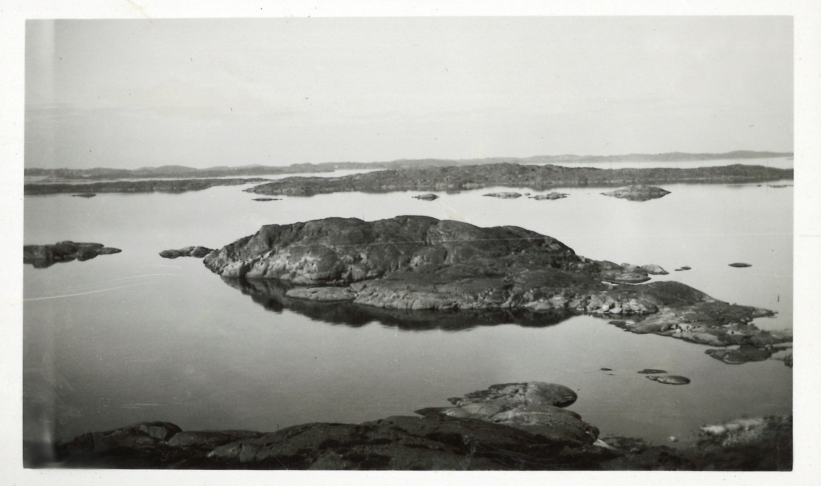 
                    Ett svartvitt fotografi av utsikten över Göteborgs skärgård. På bilden syns flera skär i havet.  
                    
