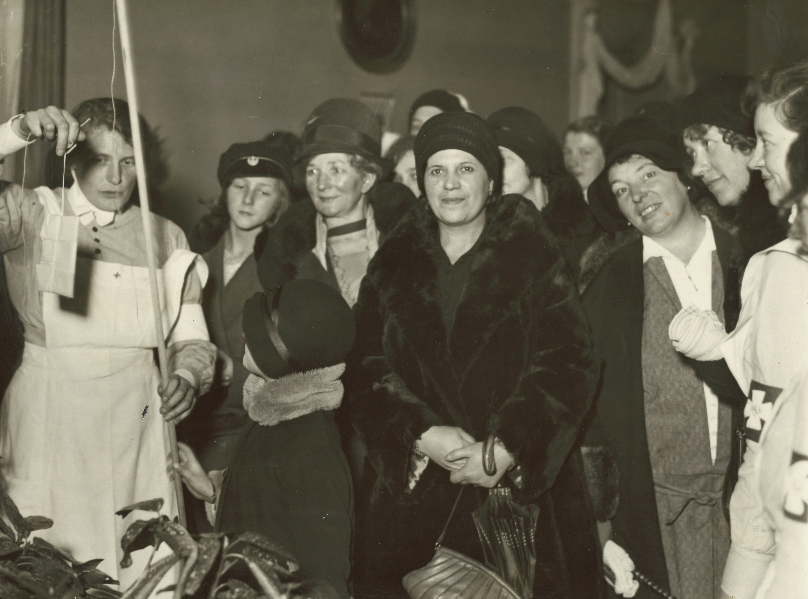 
                    Ett svartvitt fotografi från sjuksystrarna vid Sahlgrenskas julförsäljning den tredje december 1930. Till vänster i bilden syns en sjuksyster och ett barn hålla i ett metspö till försäjningens fiskedamm. En påse sitter på kroken. Flera kvinnor i ytterkläder och en sjuksyster tittar på, två av kvinnorna tittar in i kameran. 
                    